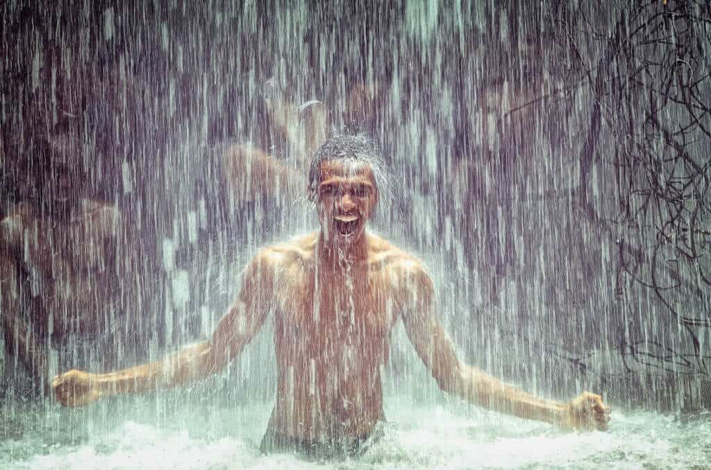Ein glücklicher Mann unter einem Wasserfall