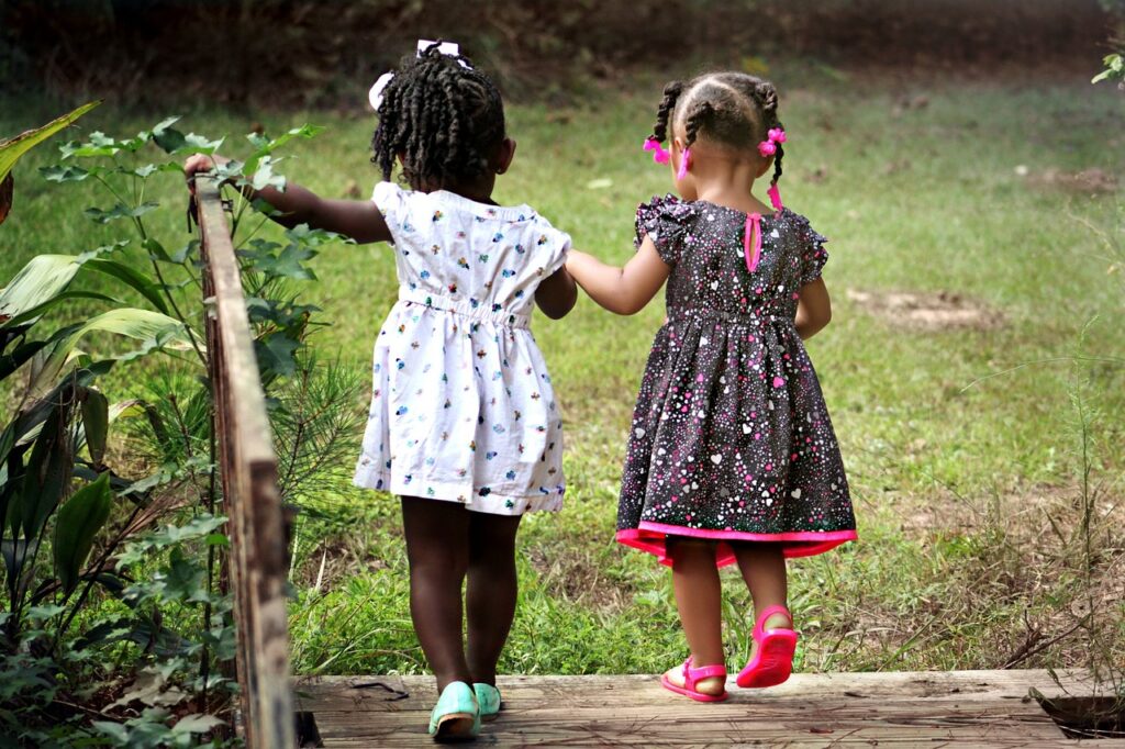 Two little girls hold hands and are therefore strong. power of the group.