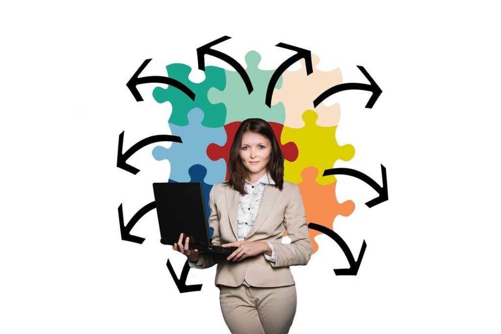 Eine Businessfrau steht mit einem Laptop vor einer Puzzlewand. Business und Life Coach. Systemischer Business coach.