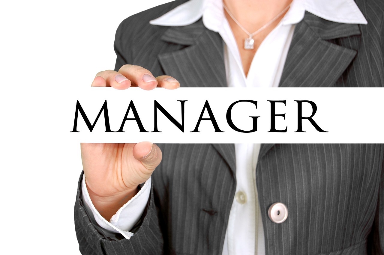 A woman holds a sign that says Manager. Executive coaching is more important now than ever.