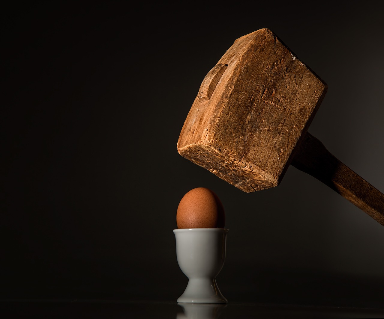 Ein Hammer, der gerade dabei ist ein Ei zu zerschlagen. Konfliktmanagement Coaching.