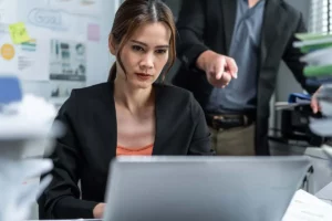 Eine Frau, die am Laptop sitzt und vom ihrem toxischen Boss attackiert wird. Toxische Kultur im Unternehmen.
